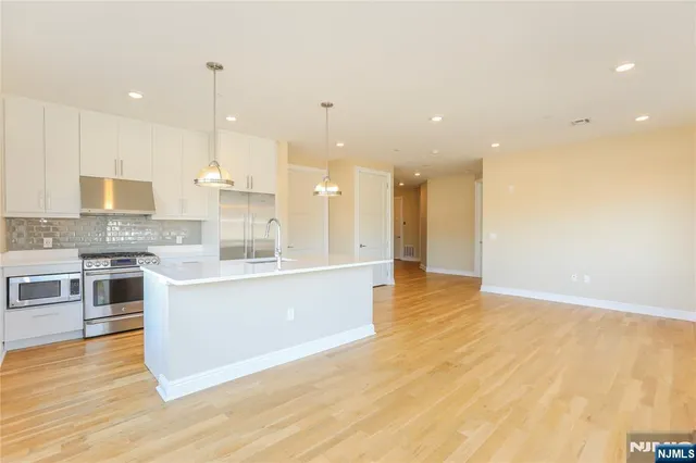 a large kitchen with stainless steel appliances kitchen island a large counter top and a wooden floors