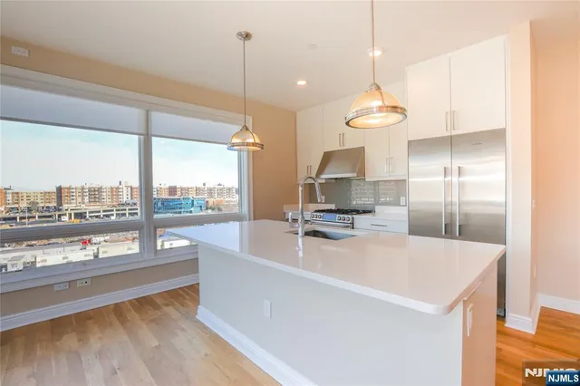 a kitchen with kitchen island a large counter top a sink a stove and a wooden floors