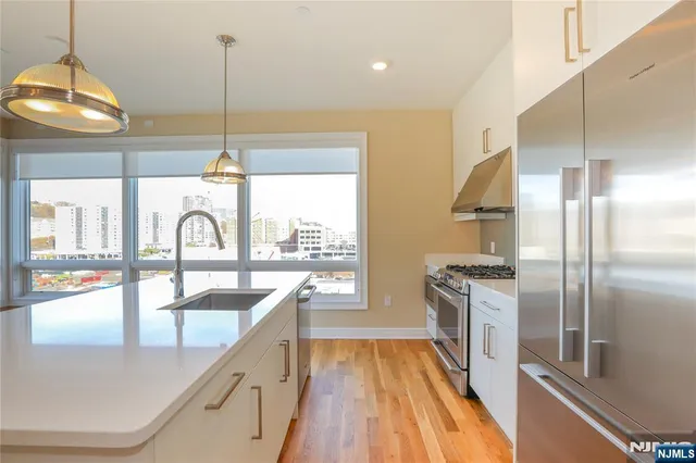 a kitchen with stainless steel appliances granite countertop a sink a stove and a wooden floors