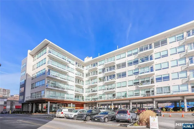 a front view of a building with lot of cars and trees