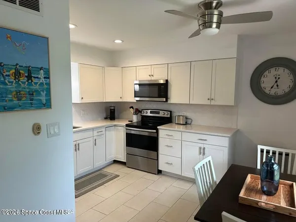 a kitchen with stainless steel appliances granite countertop a stove a sink and a refrigerator with white cabinets