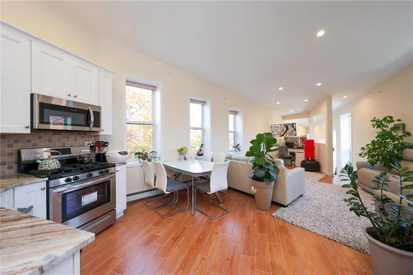 a living room with furniture wooden floor and a kitchen view