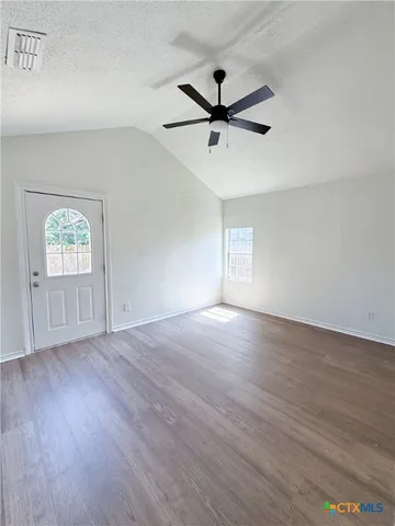 a view of empty room with wooden floor and fan