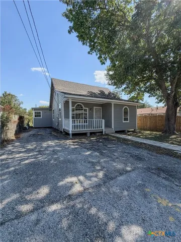 a view of a house with a yard and large tree