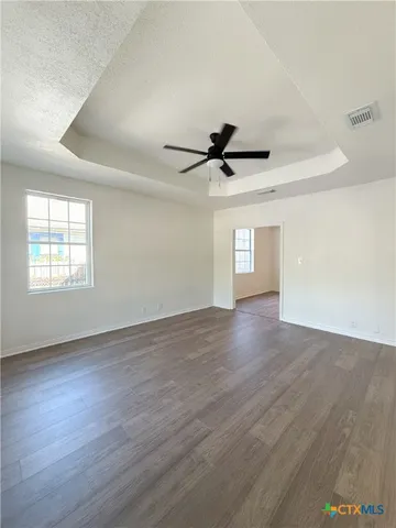 a view of empty room with wooden floor and fan