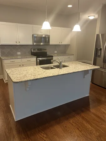 a kitchen with kitchen island granite countertop a sink a counter top space and cabinets