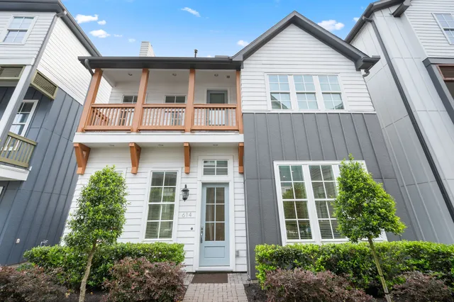 a view of a brick house with large windows and a small yard