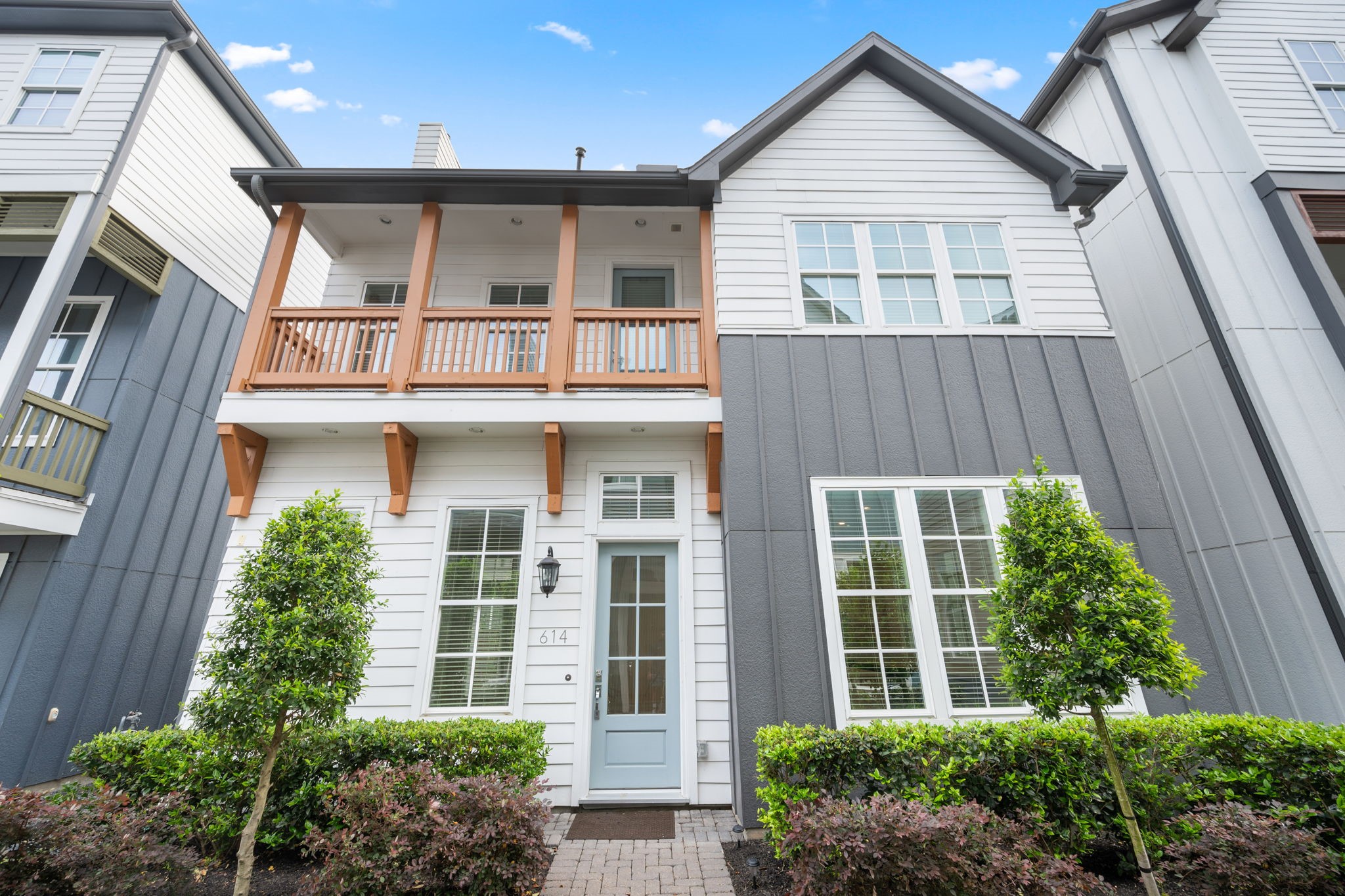 a view of a brick house with large windows and a small yard