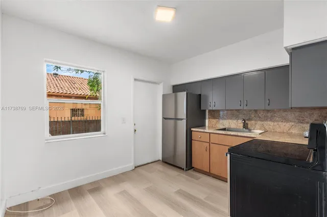 a kitchen with granite countertop a refrigerator stove top oven and sink