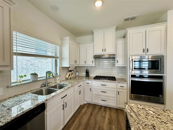 a kitchen with stainless steel appliances kitchen island granite countertop a sink stove cabinets and wooden floor