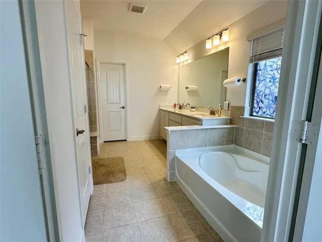 a bathroom with a tub sink and mirror