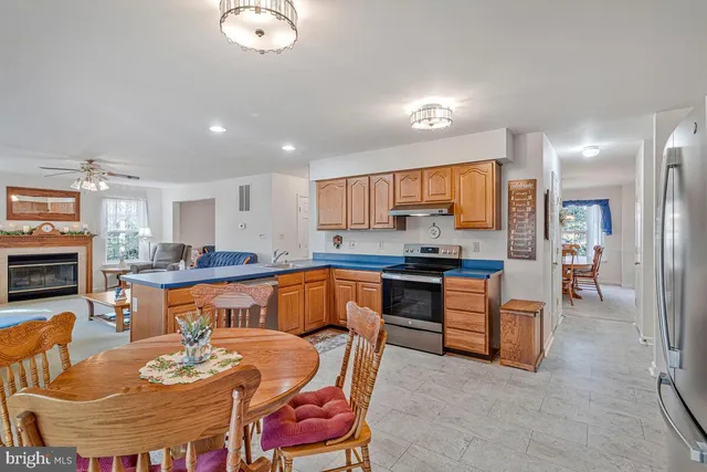 a kitchen with stainless steel appliances granite countertop a stove a sink a refrigerator dining table and chairs