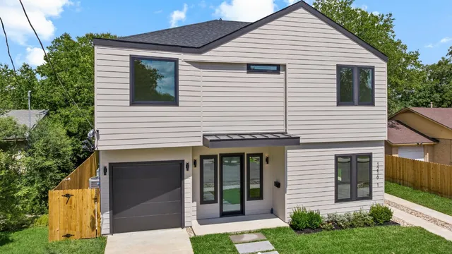 a view of a white house with large windows and a small yard