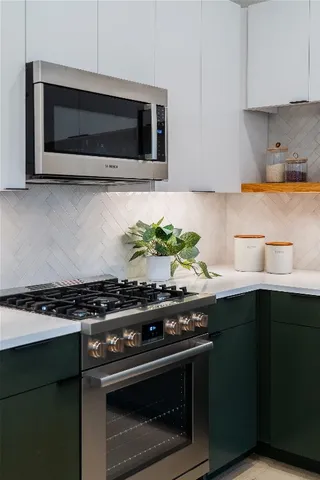 a kitchen with stainless steel appliances a stove a microwave a sink and cabinets