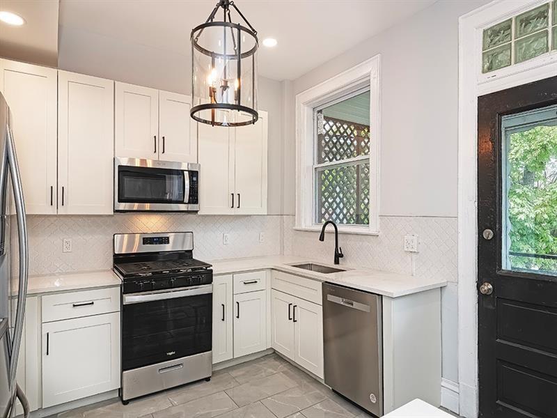 923 Adelaide Street Pittsburgh, PA 15219 - Photo 13 of 32 a kitchen with white cabinets stainless steel appliances and window