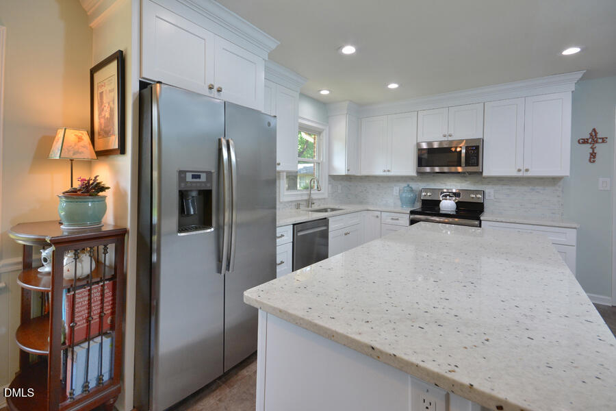 313 Andover Road Durham, NC 27712 - Photo 12 of 36 a kitchen with a refrigerator a stove and a sink with wooden floor