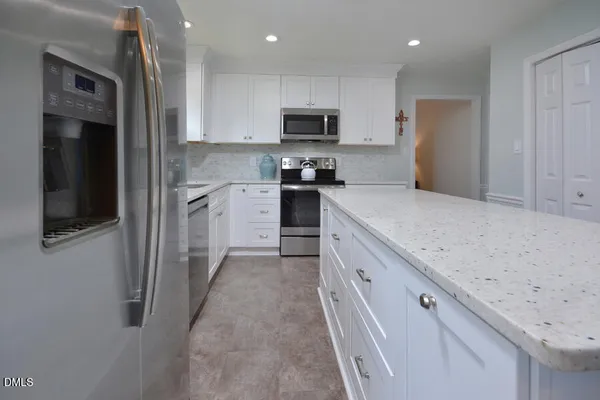 a kitchen with stainless steel appliances white cabinets granite counter tops and a stove top oven