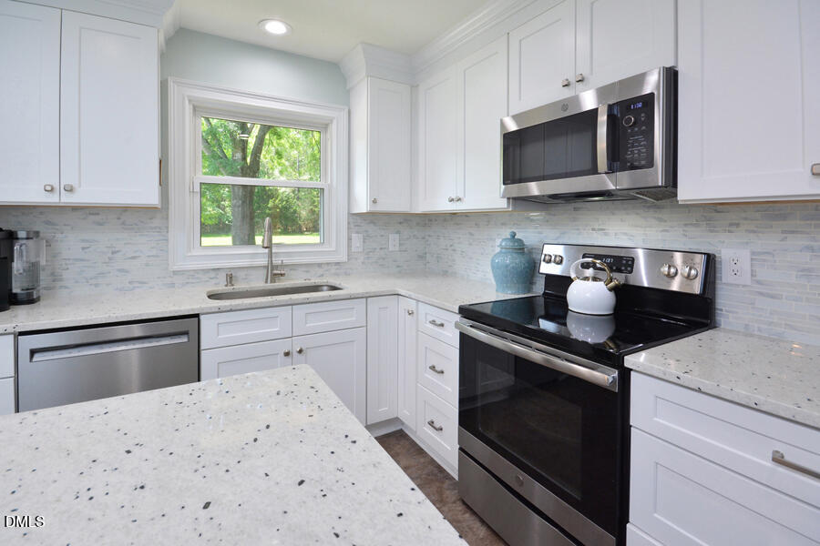 313 Andover Road Durham, NC 27712 - Photo 14 of 36 a kitchen with stainless steel appliances white cabinets granite counter tops and a stove top oven