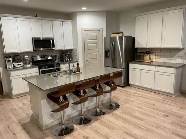 a kitchen with stainless steel appliances a kitchen island a stove a table and chairs in it
