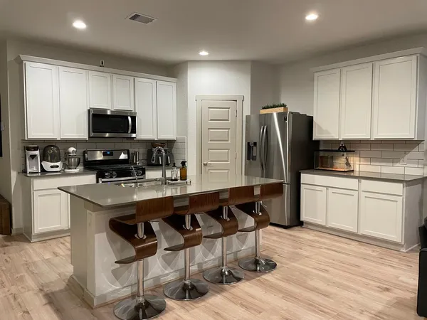 a kitchen with stainless steel appliances granite countertop a sink a stove a refrigerator a microwave and cabinets
