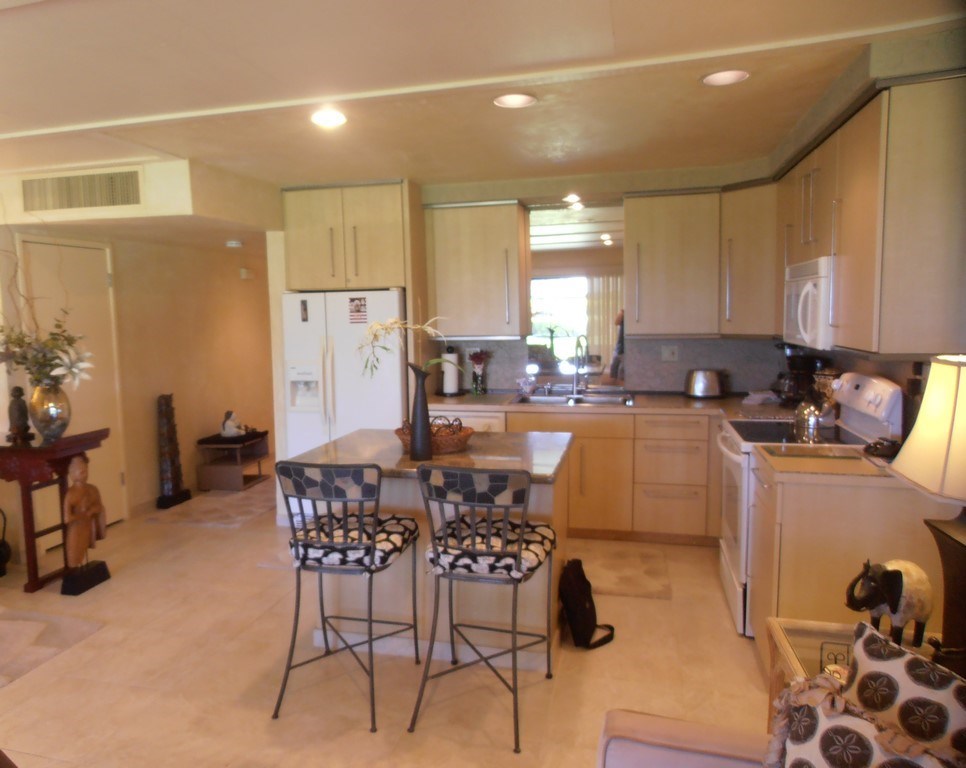 12 South Kihei Road, Unit G5 Kihei, HI 96753 - Photo 12 of 28 a kitchen with a dining table chairs cabinets and stainless steel appliances