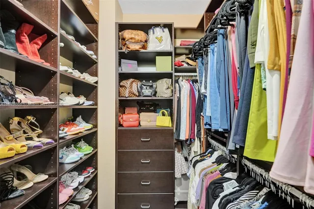 a view of walk in closet with clothes and shoes