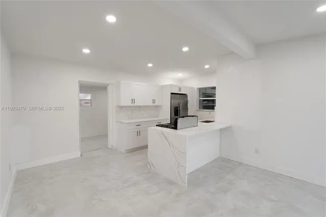 a large white kitchen with a refrigerator a stove top oven a white counter space and cabinets