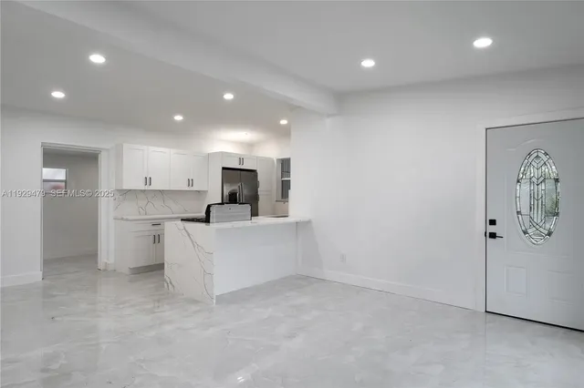 a view of a kitchen with kitchen island white cabinets and refrigerator