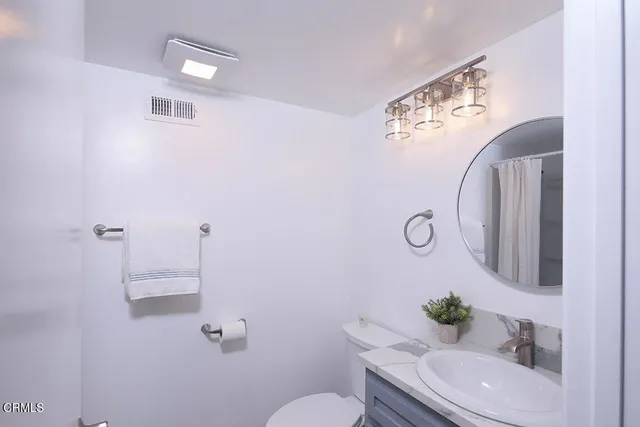 a bathroom with a granite countertop toilet sink and mirror