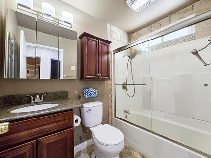 a bathroom with a granite countertop sink toilet mirror and shower