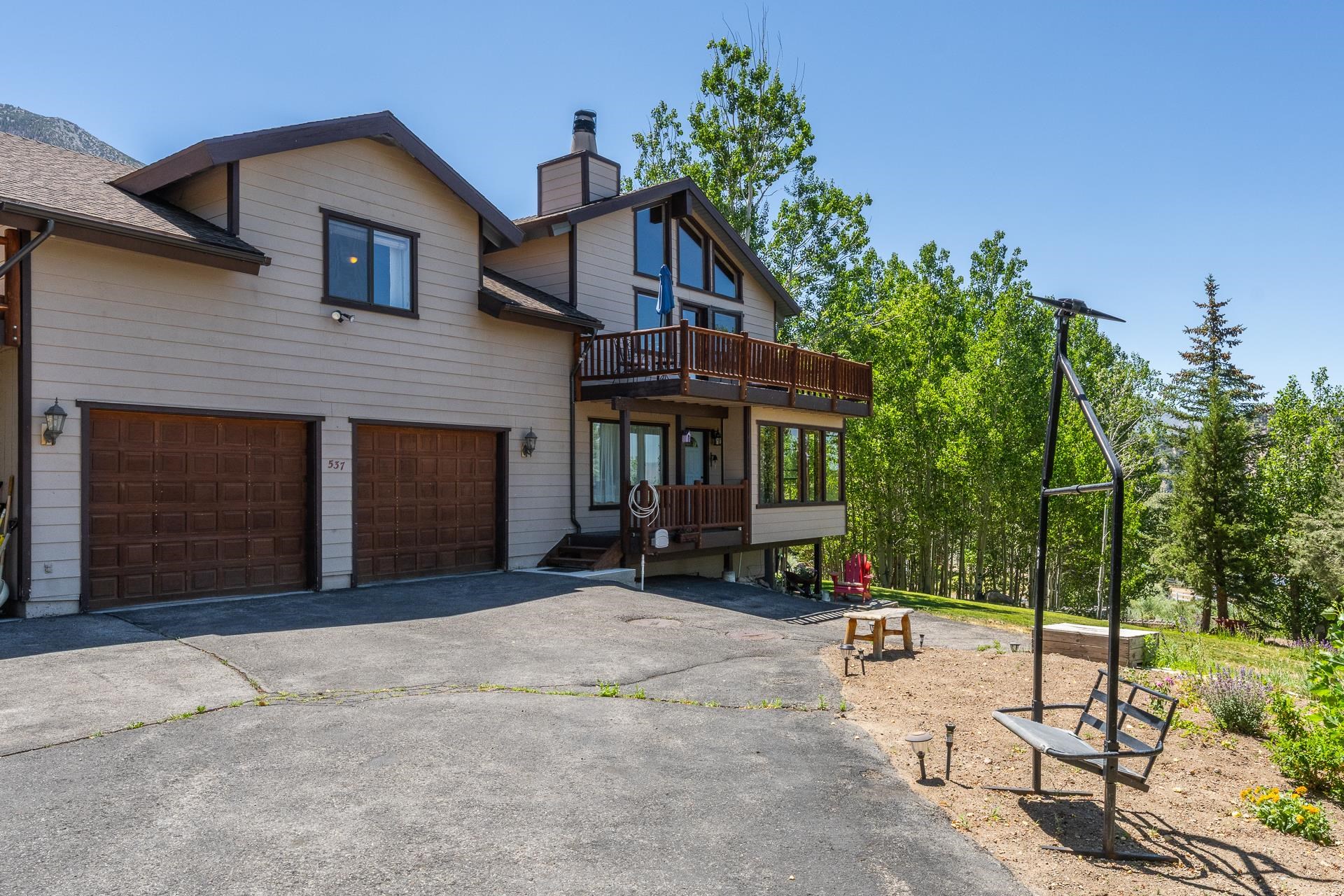 537 Aspen Spring Ranch Road Mammoth Lakes, CA 93546 - Photo 3 of 40 Exterior showcasing multiple levels, a two-car garage with paneled doors, and a second-story balcony with wood railing