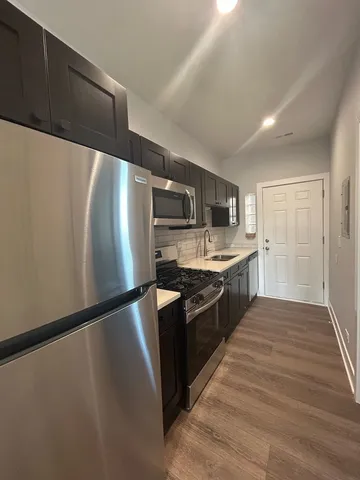 a large kitchen with stainless steel appliances a refrigerator and a stove top oven