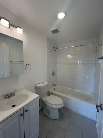 a bathroom with a bathtub shower sink mirror vanity and toilet