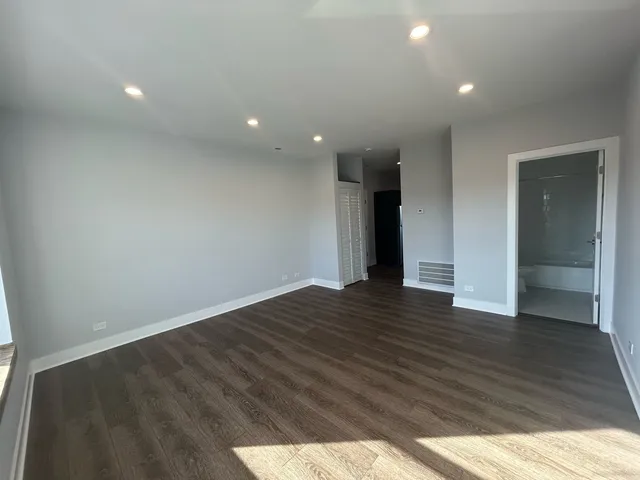 a view of an empty room with wooden floor and closet