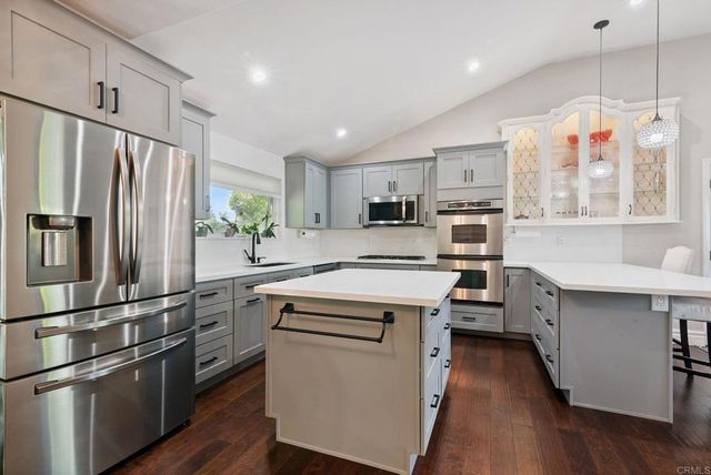 a kitchen with stainless steel appliances sink stove refrigerator and wooden floor