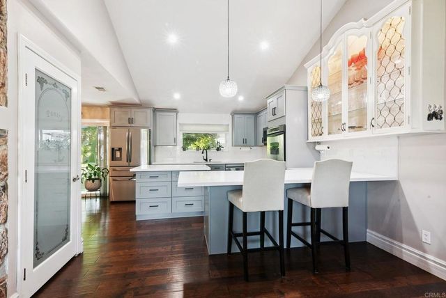 a kitchen with a table chairs wooden floors and a view of living room