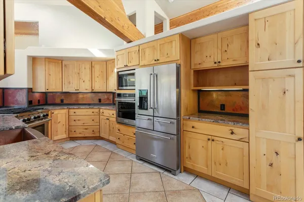 a kitchen with stainless steel appliances granite countertop a refrigerator stove and white cabinets