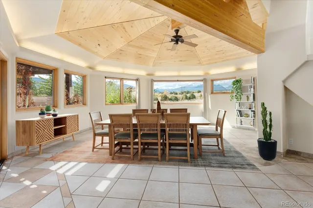 a view of a dining room and livingroom with furniture a floor to ceiling window and potted plants