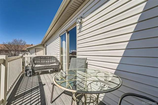 a balcony with table and chairs with wooden floor and fence
