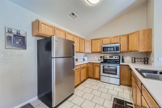a kitchen with stainless steel appliances granite countertop a refrigerator stove and sink