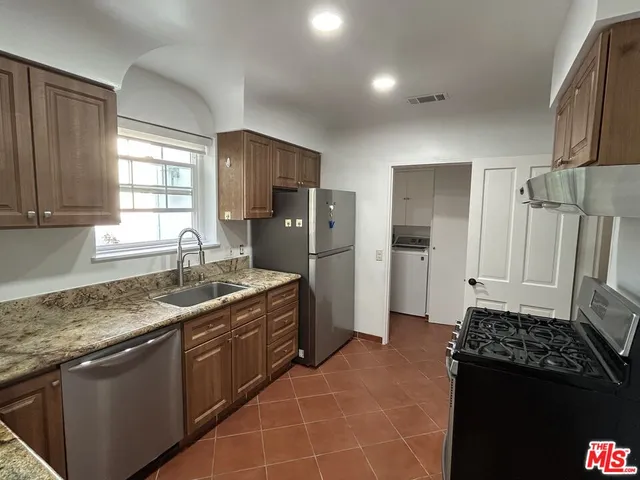 a kitchen with granite countertop a refrigerator and a sink