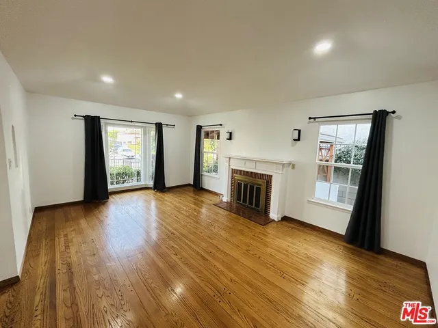 an empty room with wooden floor and fireplace