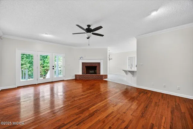 an empty room with wooden floor fan and windows
