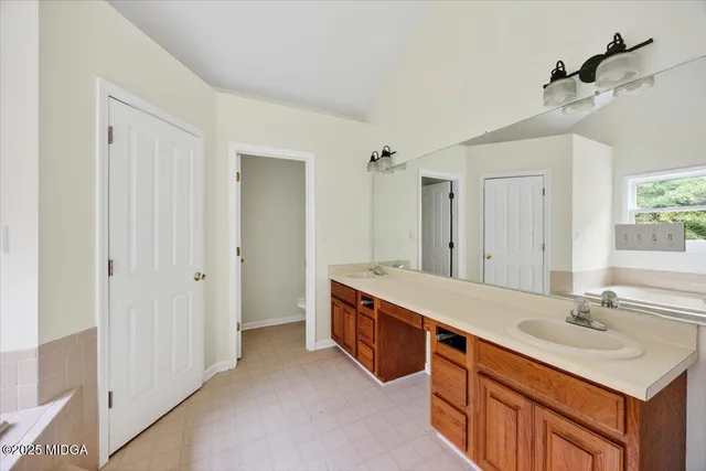 a bathroom with a sink double vanity granite tub shower and a mirror