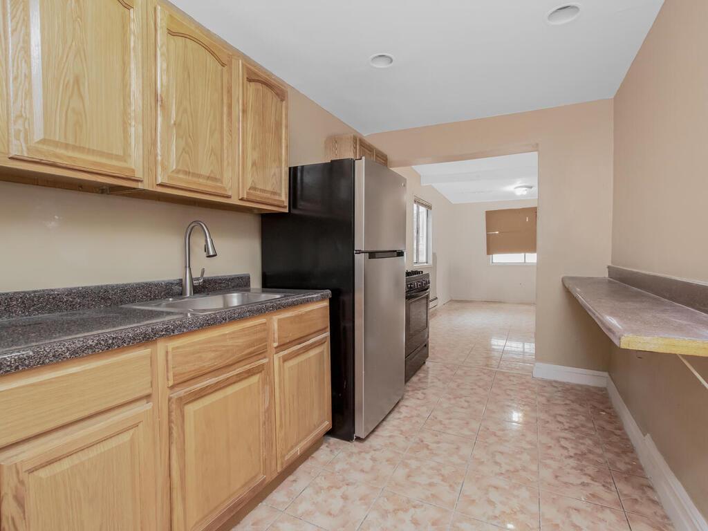 3357 Perry Avenue Bronx, NY 10467 - Photo 14 of 31 Kitchen with a sink, freestanding refrigerator, light brown cabinets, black gas stove, and dark countertops