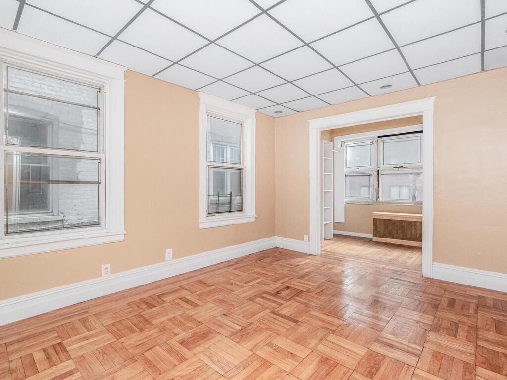 3357 Perry Avenue Bronx, NY 10467 - Photo 21 of 31 Empty room featuring radiator heating unit, baseboards, and a drop ceiling