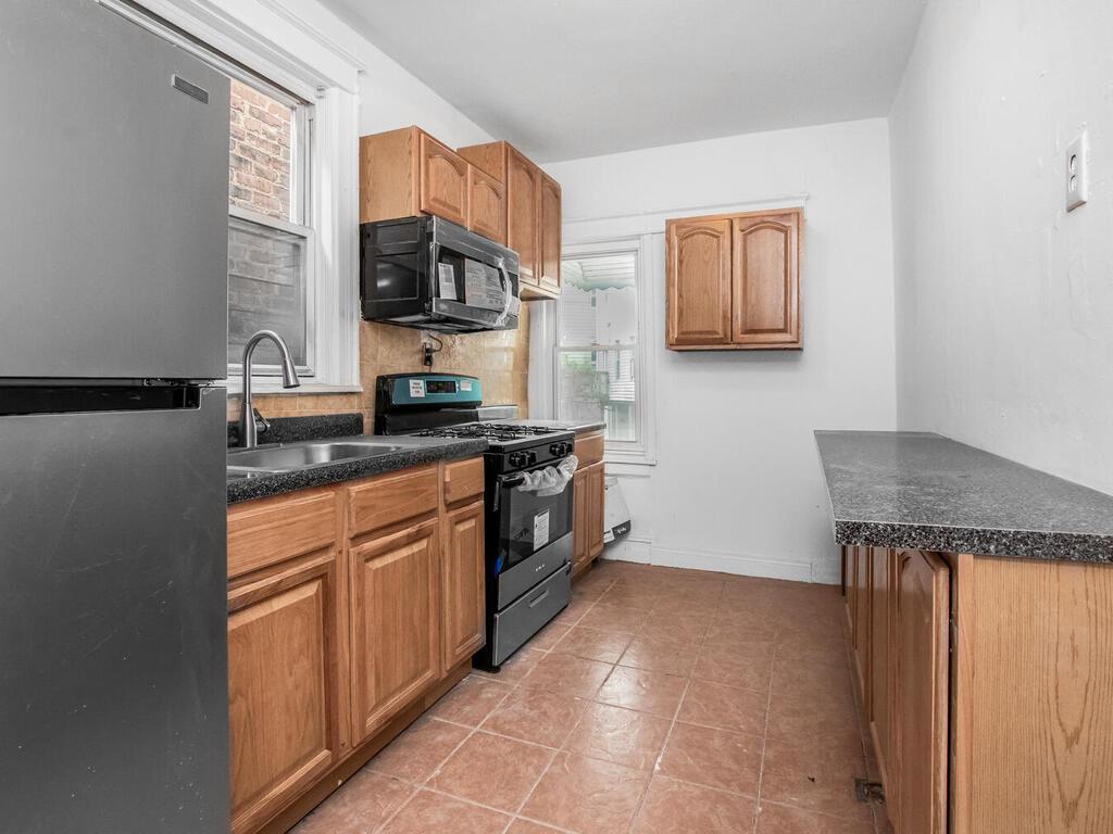 3357 Perry Avenue Bronx, NY 10467 - Photo 5 of 31 Kitchen featuring range with gas cooktop, a sink, dark countertops, freestanding refrigerator, and black microwave