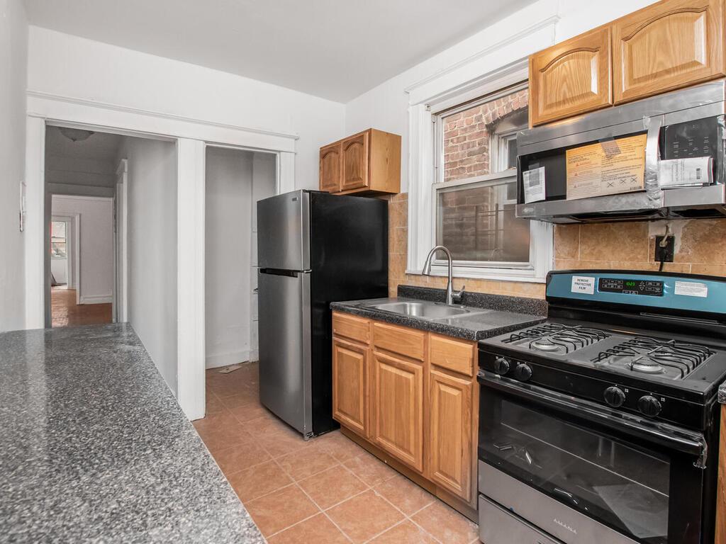 3357 Perry Avenue Bronx, NY 10467 - Photo 6 of 31 Kitchen featuring decorative backsplash, dark countertops, appliances with stainless steel finishes, a sink, and light tile patterned floors