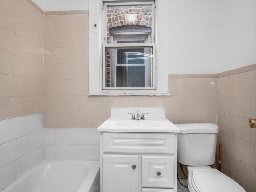 3357 Perry Avenue Bronx, NY 10467 - Photo 7 of 31 Bathroom with tile walls, toilet, vanity, and a bath