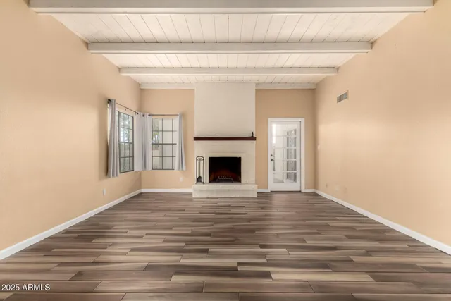 a view of empty room with wooden floor and fireplace
